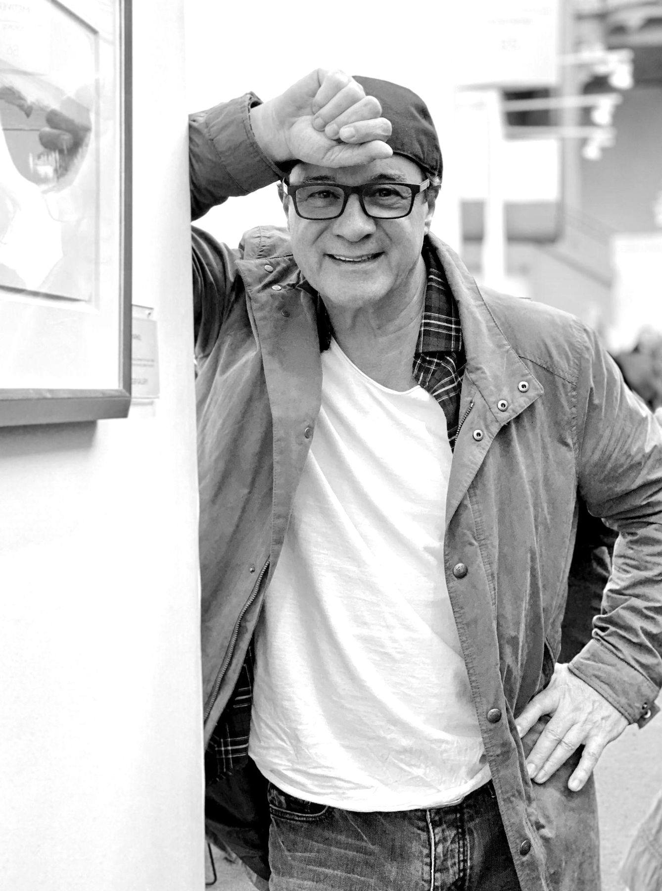 Jehan Legac, seated, wearing a black jacket and sunglasses.